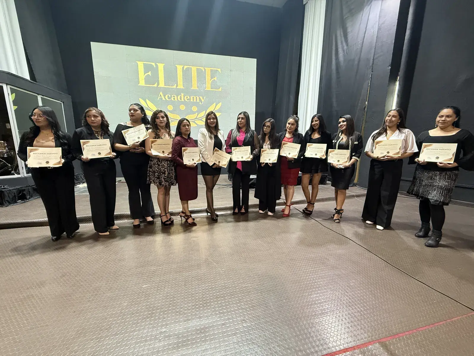 Grupo de alumnas con certificados sobre el escenario